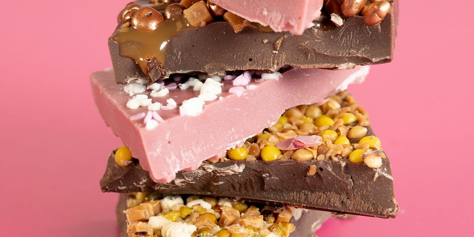 inclusion chocolate stacked on top of each other with a pink background