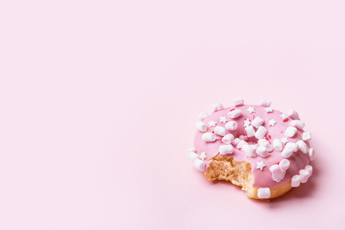 a pink donut with pink background with a bite taken out of it